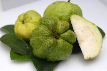 a group of fresh ripe Crystal guava (Psidium guajava) on green leaves isolated on white background.