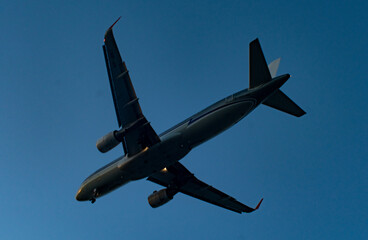 The silhouette of a passenger plane coming in for landing against the backdrop of the sunset sky.