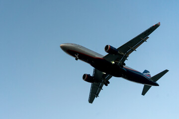 The silhouette of a passenger plane coming in for landing against the backdrop of the sunset sky.