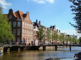 Canal in Amsterdan (Netherlands) a bridge and people in which we can see the arquitecture of amsterdam's house.