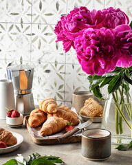 Breakfast with croissants, coffee, peonies flower, honey composition with tile background