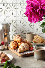 Breakfast with croissants on wooden tray, coffee, peonies flower, honey composition with tile background