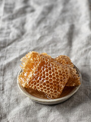 Honey in honeycombs close up in a saucer on linen tablecloth, text space