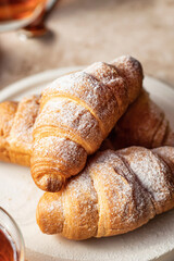 Fresh croissants for breakfast on brown background close up