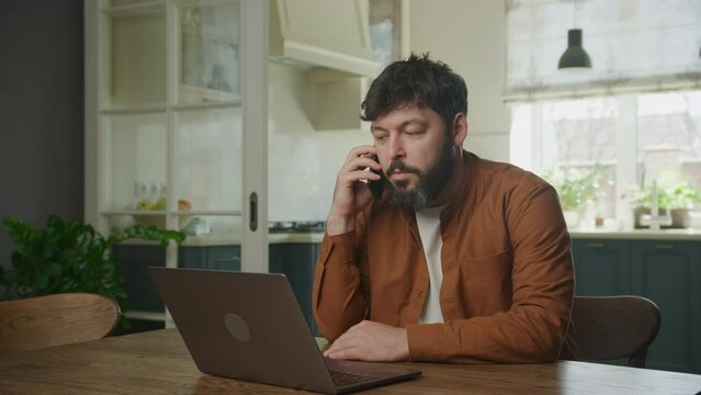 Peforming a sale on his phone in front of a laptop computer. Man recieving good news on phone
