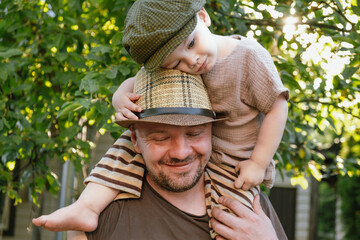 Cute little son sitting on his father's shoulders. Happy dad and toddler son spending time together...