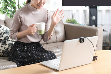 パソコンの前で手を振る若いアジア人の女性
