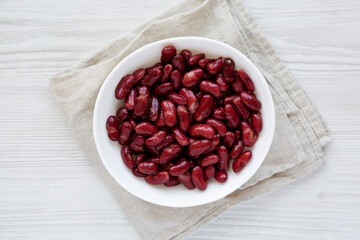 Red Organic Kidney Beans in a White Bowl on a white wooden surface, top view. Flat lay, overhead, from above.