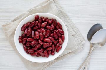 Red Organic Kidney Beans in a White Bowl on a white wooden surface, top view. Flat lay, overhead, from above.