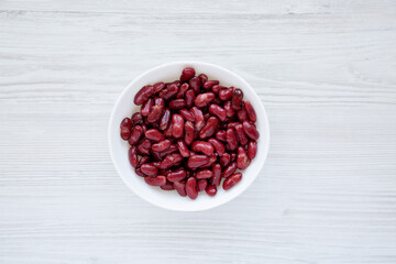 Red Organic Kidney Beans in a White Bowl on a white wooden surface, top view. Flat lay, overhead, from above.