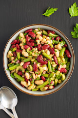 Homemade Three Bean Salad in a Bowl on a black surface, top view. Flat lay, overhead, from above.