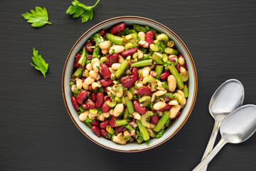 Homemade Three Bean Salad in a Bowl on a black surface, top view. Flat lay, overhead, from above.