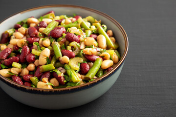 Homemade Three Bean Salad in a Bowl on a black background, side view.