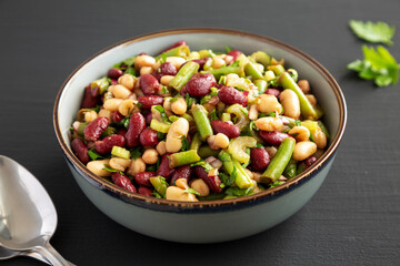 Homemade Three Bean Salad in a Bowl on a black background, side view.