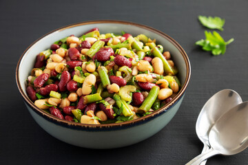 Homemade Three Bean Salad in a Bowl on a black background, side view.
