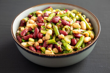 Homemade Three Bean Salad in a Bowl on a black background, side view.