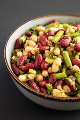 Homemade Three Bean Salad in a Bowl on a black background, side view.