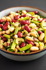 Homemade Three Bean Salad in a Bowl on a black background, side view.