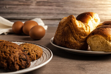 horizontal photo of eggs, pastries, brioches, cookies on wooden table and wooden background side lighting