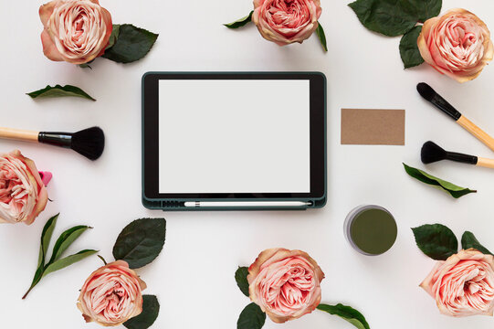 Creative workplace layout with blank screen tablet, flowers, business card. Female workspace mockup