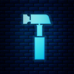 Glowing neon Hammer icon isolated on brick wall background. Tool for repair. Vector