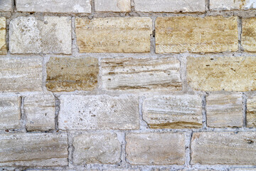 An old damaged wall made of white, gray and yellow bricks as a background
