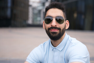 Portrait of happy positive Arab Muslim ethnic guy, young man with black beard in sunglasses and...