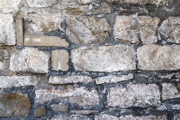 A dirty white wall made of natural stones of different size and shape as a background