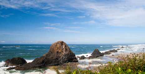 Pacific ocean shore with the rocks in turquoise waters, calm waives and green bushes