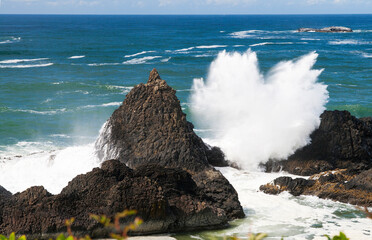 Turquoise waters of the Pacific Ocean with waves hitting rocks dispersing multiple airdrops