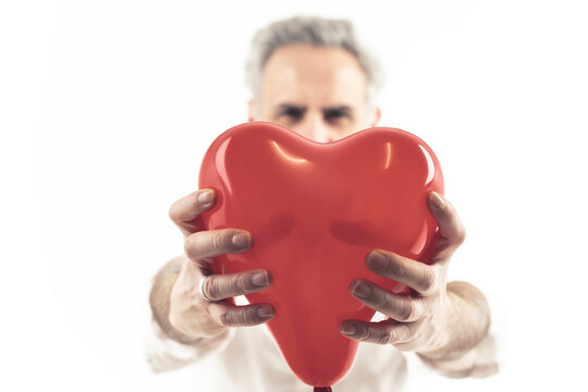 middle aged grey haired man holds heart shaped balloon isolated white background medium shot . High quality photo