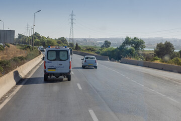 Fototapeta na wymiar Motorway in algeria, around the city of Oran. View of cars in african city traveling on multi lane highway.. Police car in front