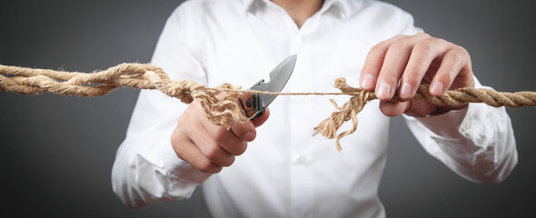 Man with knife cutting frayed rope. Risk