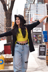 Fototapeta premium Happy stylish young girl in fedora hat dancing on the street