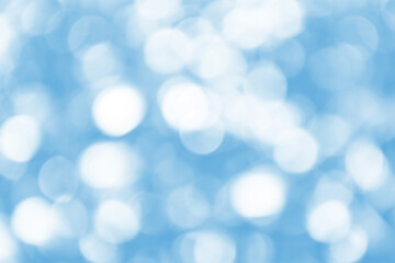 Obraz premium Defocused Bright abstract blue winter background with shimmering white sunspots. Bokeh. Holiday festive concept. Copy space for text. Merry Christmas and Happy New Year