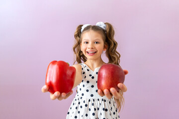 Fototapeta na wymiar A little girl holds out an apple and a red pepper forward. Vegetables and fruits for children's health.