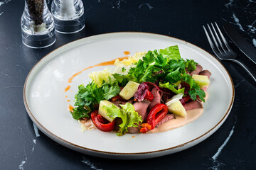 Fresh salads with beef steak, green leaves, arugula and sweet sauce on dark background