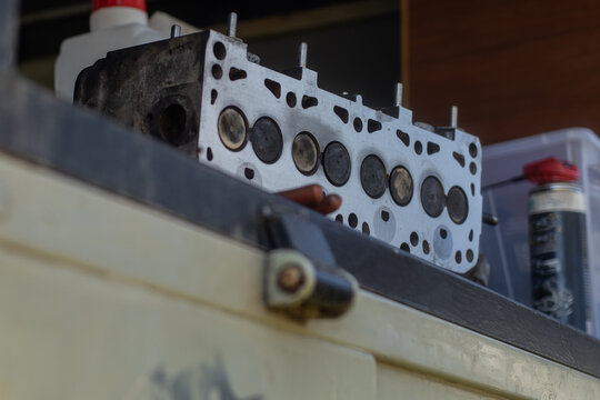Old cylinder head of a 8V diesel engine sitting on a bench or atable. Visible combustion side of a cylinder head, just milled or straightened.