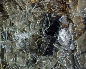 Broken glass and an old model of a mobile phone with buttons.