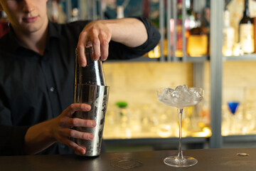 bartender prepares a cocktail in a bar, club. pours alcohol and syrups. uses ice and breaks ice