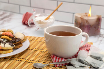 breakfast or snack with a cup of tea fine doughs of cornstarch chocolate vanilla and dulce de leche on a marble table with sugar bowl and decorative candle