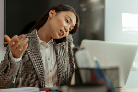 Bussy Asian Woman Worker Talk Phone With Client Sit On Her Workplace In Office. High Quality Photo