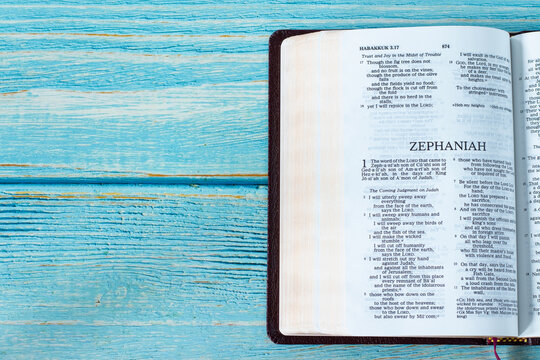 Zephaniah open Holy Bible Book on a rustic wooden background with copy space. Top table view. Old Testament Scripture prophecy study, Christian biblical concept.	