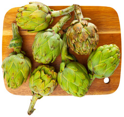 Obraz premium Fresh ripe artichokes lying on a cutting board. Ingredients for cooking. Isolated over white background