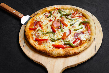 Pizza de carne salami y vegetales en bandeja de madera