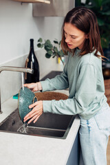 Woman washing dishes in the kitchen sink