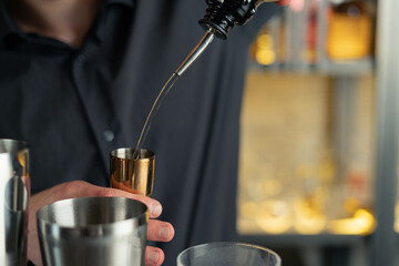 bartender prepares a cocktail in a bar, club. pours alcohol and syrups. uses ice and breaks ice