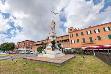 A seagull flies over the historic statue, Monument of the Four Moors which depicts the duke Ferdinand I with four Moorish slaves as reminder of Livorno's slave market, at the port of Livorno, Italy. - obrazy, fototapety, plakaty