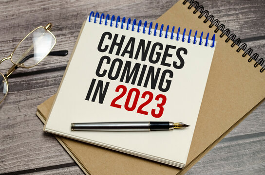 notebook with the word change is coming in 2023 on wooden background
