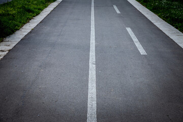 Obraz premium Selective blur on white road markings indicating the presence of a bicycle lane, made of black asphalt, designed for bikers, bikes and bicycles to drive safely in an urban environment...